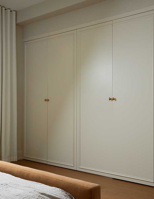 A large closed built in wardrobe in white with gold details. serene city retreat