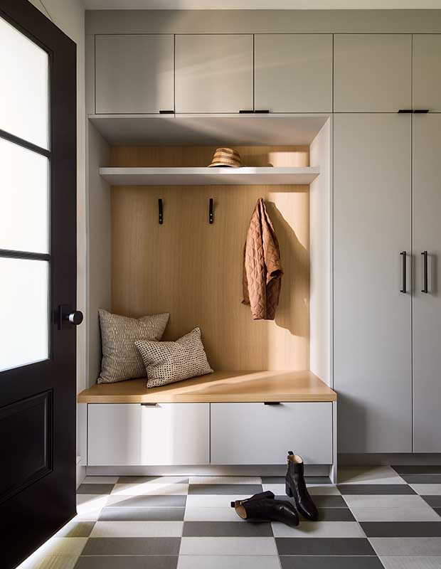 A light wood mudroom with clean-lined white cabinets and checkerboard tiles. english cottage-style house