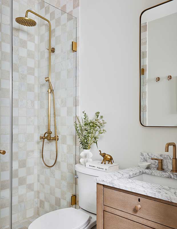 a minimal bathroom with gold hardware accents, checkerboard tile, marble countertops, and white walls. serene muskoka bunkie