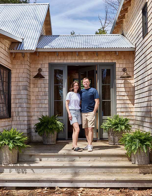 A caucasian couple stand outside a classic cottage. wood-clad family cottage