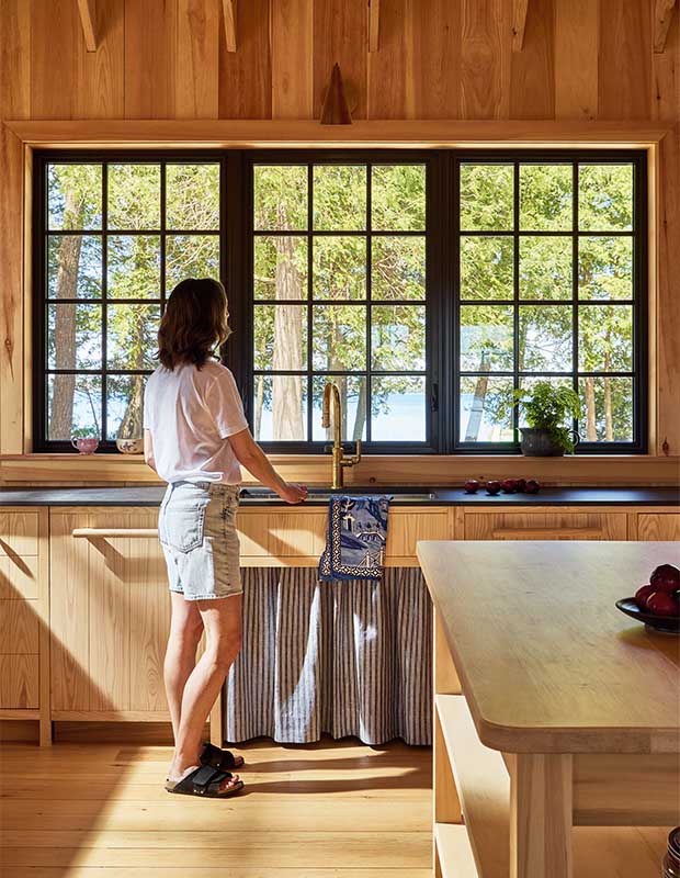 Designer Angela Wheeler takes in the lake views from her kitchen sink window. wood-clad family cottage