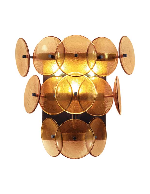 A photo of a statement sconce with discs of pressed amber glass encircling a black centre holding lightbulbs.