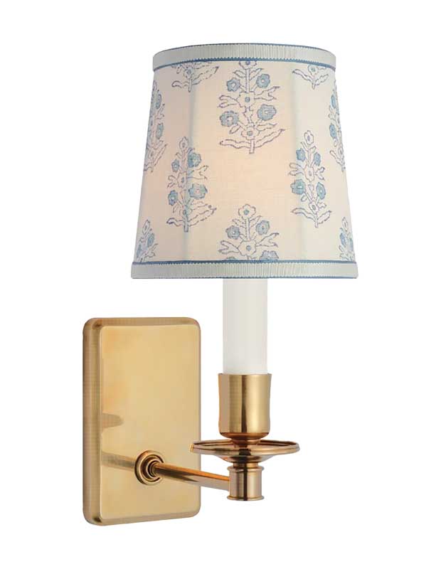 A photo of a statement sconce with a brass wall mount and a traditional white lampshade with a light blue embroidered floral motif.