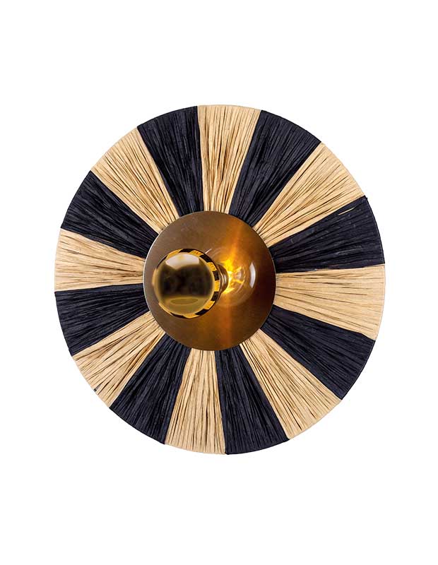 A photo of a circular statement sconce against a white background. The centre is a brass circle with a bulb in the middle, and outwardly-radiating rays of black and white fabric stretch to the edges.