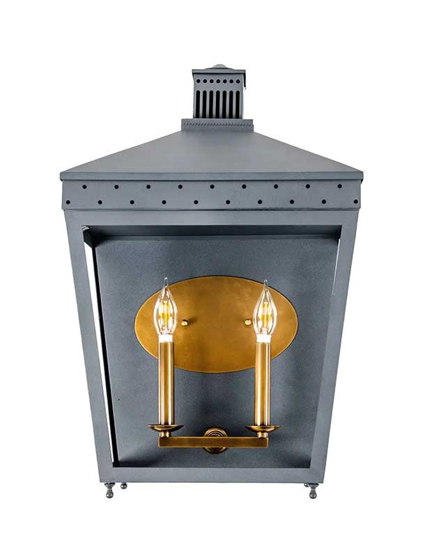 A photograph of a lantern-style statement sconce with a black exterior and brass fixtures inside.