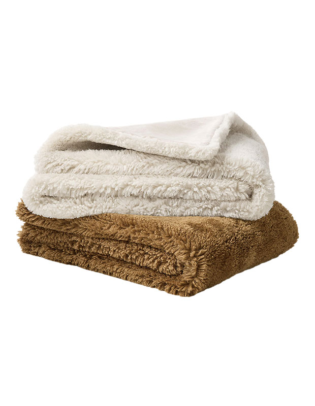 A folded white stylish throw sits atop a folded brown throw against a white background.