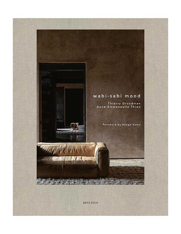 A cover of design book "Wabi-Sabi Mood." The title is superimposed in small letters over a photo of a couch with a hallway behind it.