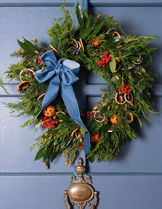 A photograph of a holiday craft: a green wreath with a blue bow against a blue door.