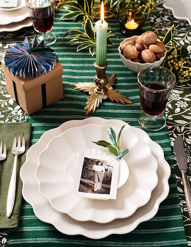 A photograph of a holiday craft: A black and white photograph sits on white plates set on a green striped tablecloth.