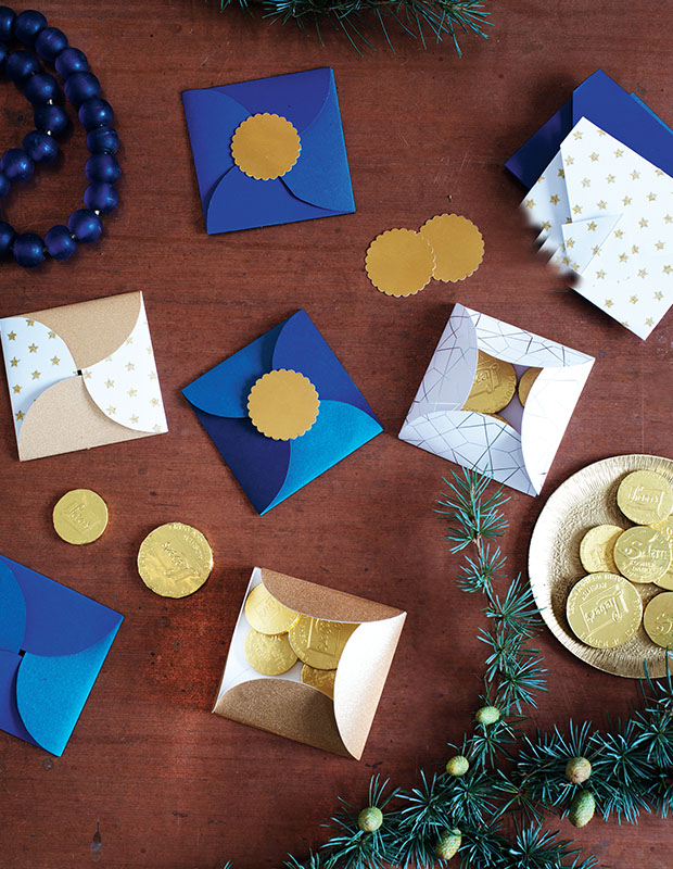 A photograph of a holiday craft: blue cards with gold seals sit on a wooden tabletop.