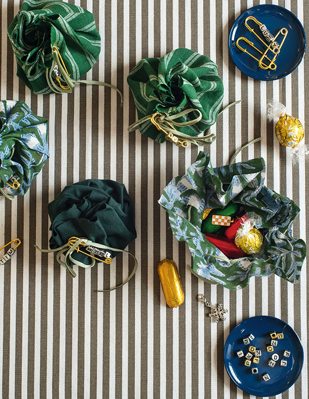 A photograph of a holiday craft: gifts wrapped in cloth sit on a striped tablecloth.