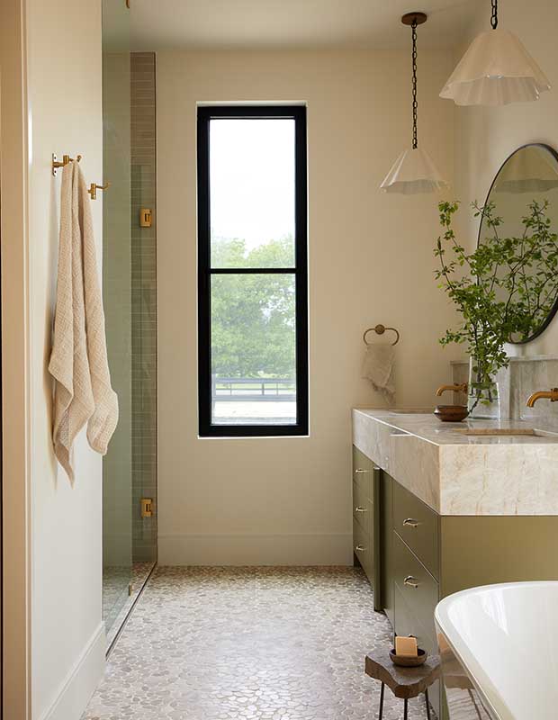 Photo of house featuring English design: A bathroom featuring a narrow window with a black frame and a vanity with green plants on it.