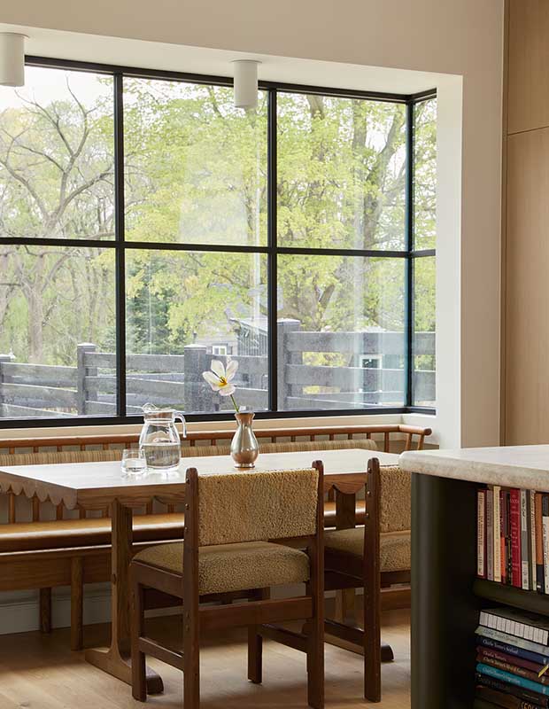 Photo of house featuring English design: A view of a banquette with chairs in front of a large window with black muntins.