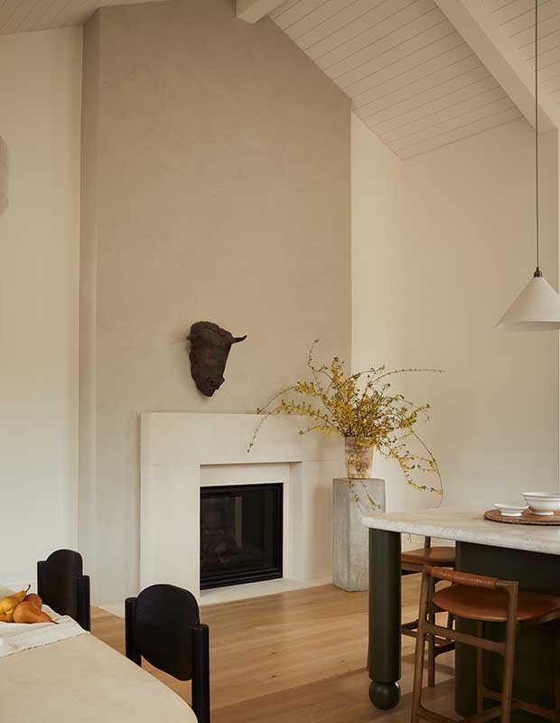 Photo of house featuring English design: A bust of a bull hangs over a white fireplace against beige walls.