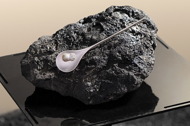 A freshwater pearl from the Scottish River Tay sits on a black rock.